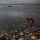 Un hombre lavándose los brazos usando agua contaminada en la bahía de Guanabara. Foto: Felipe Dana / AP Images.